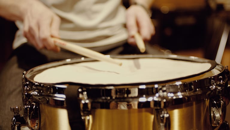Drumsticks hitting a snare drum